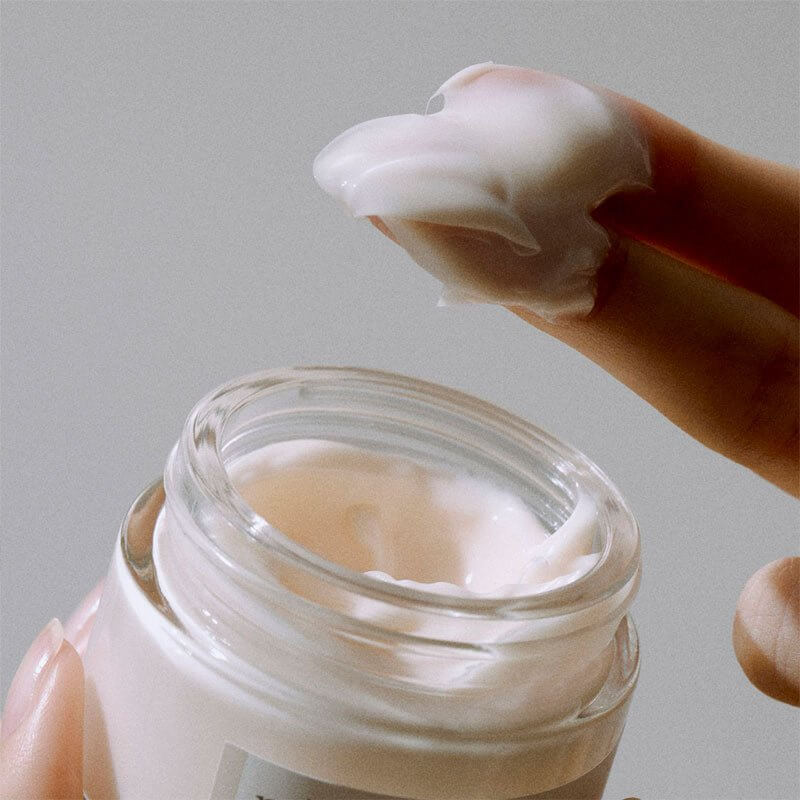 K-beauty fermented bean cream in a jar with a creamy texture on a finger.
